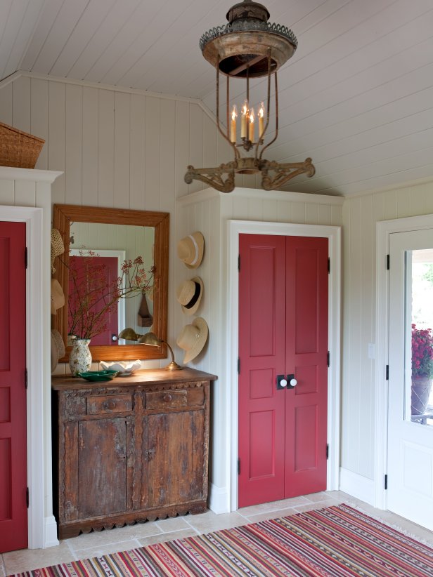 White Mudroom With Two Closets With Red Doors and Antique Dresser