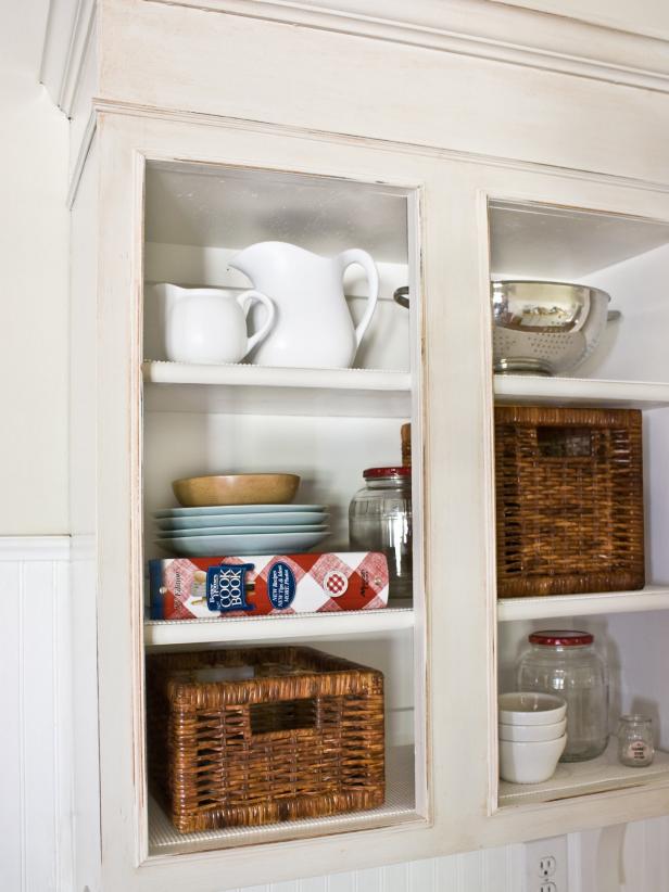 Antiqued white kitchen cabinet with exposed shelves and kitchenware.