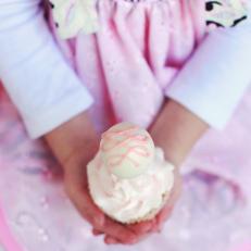 Girl Holds a Cupcake with a Cake Pop