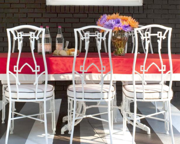 Outdoor Dining Table With Red Tablecloth and White Iron Chairs