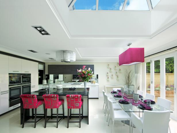 Open Kitchen With Glass Dining Table Next to Pink Barstools