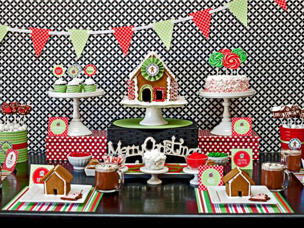 Classic gingerbread houses and cupcakes are displayed on cake stands and wrapped boxes to create a holiday dessert buffet inspired by the colors and flavors of the season.