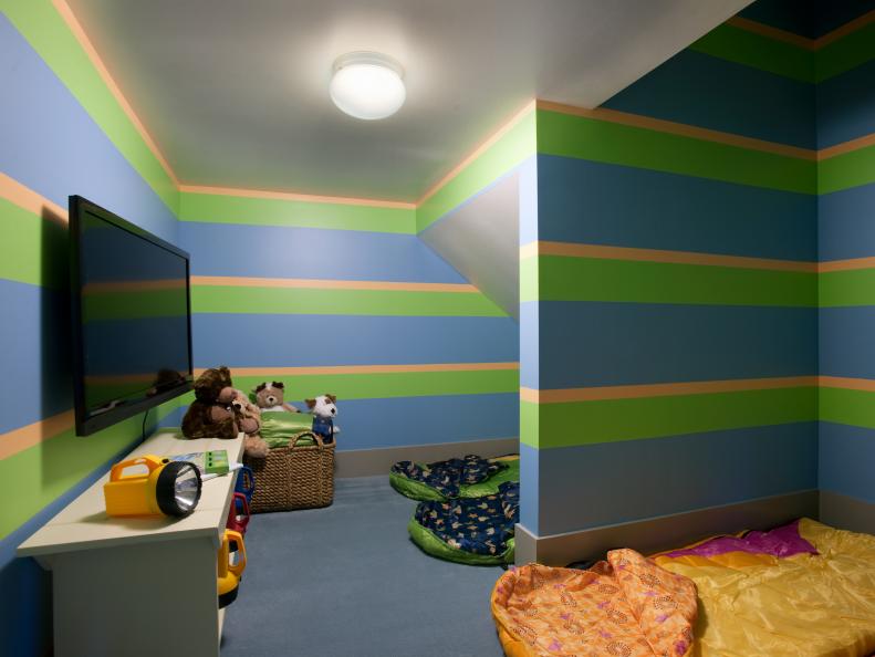 Kids' Basement Playroom With Striped Walls, TV and White Bookcase