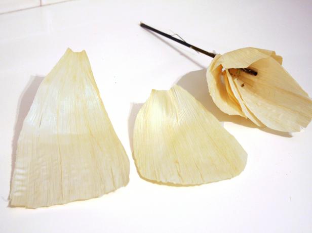 Using scissors, round edges of four to six cornhusks to resemble flower petals. Working in an overlapping, concentric pattern, hot glue cornhusk petals to skewer/plant stake.
