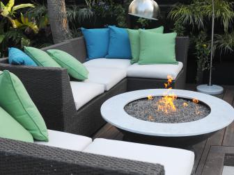 Brown Wicker Sofa With Blue & Green Pillows by Outdoor Fire Pit