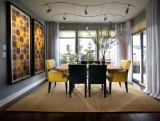 Gray Dining Room With Black and Yellow Dining Chairs and Colorful Art