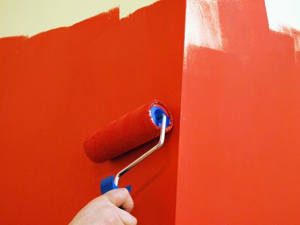 Orange paint being rolled on a wall. 