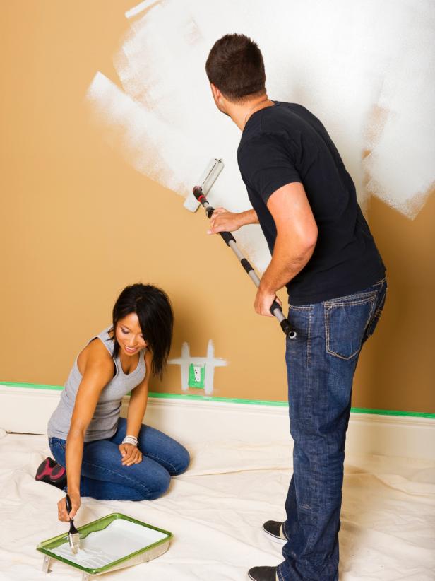 Two people priming walls with rollers.