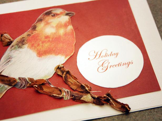 An image of a bird, cut from another source, has been affixed to a handmade holiday greeting card and adorned with pieces of pine cone, tied up with string.