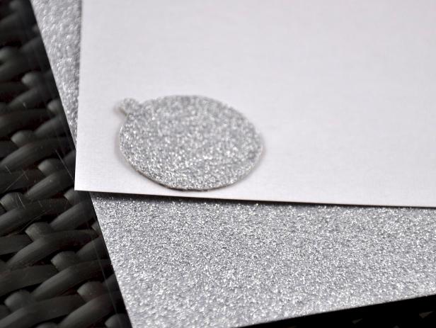 To create the pop out in the joy card you'll make three ornaments of different materials, including this decorative glitter paper.