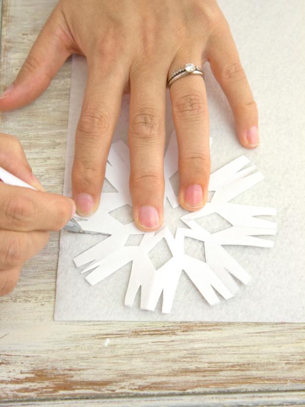 Use a pen to trace the shape of several different snowflakes onto the felt.
