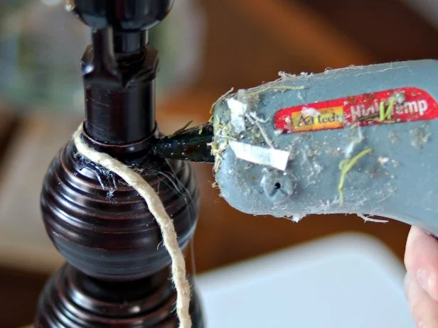 Preheat hot glue gun. Working from the top of the lamp base, apply hot glue in small sections and wrap twine around lamp.