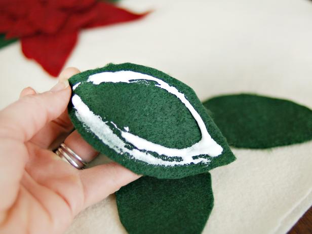 Apply fabric glue to the back of each leaf and stick it to the cream felt in the desired position.