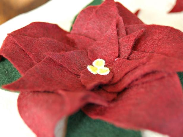 Apply fabric glue to the back of circles and stick them in a cluster to the center of each poinsettia. Allow fabric glue to fully dry before assembling pillow.
