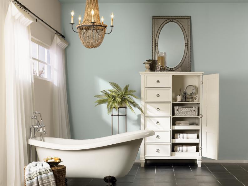 Light Blue Bathroom With White Chest, Clawfoot Tub and Chandelier