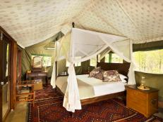 A bedroom in a tent with traditional furniture and patterened fabrics.