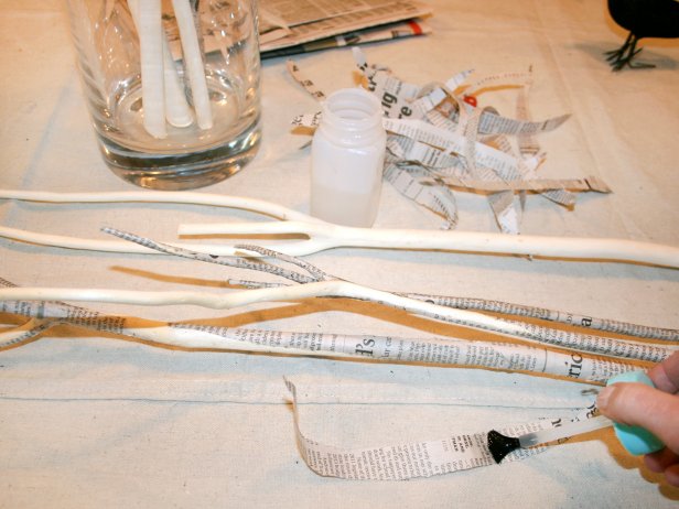 Brush decoupage glue onto lengths of torn newspaper. Wrap glued paper along branches and press into place. Repeat until branches are entirely covered, then arrange them in a tall narrow vase to dry.