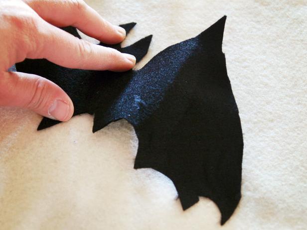A DIY Halloween applique pillow has fabric bats attached.