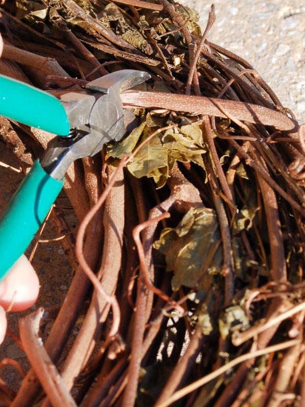 Fill urn with dirt, gravel or rocks. Clip and remove vine that holds grapevine wreaths together.