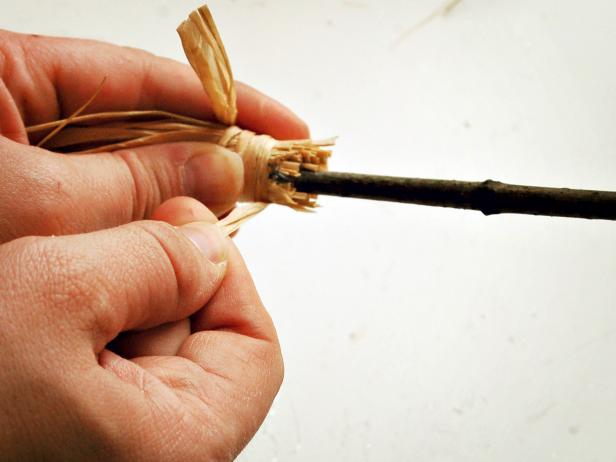 Wrap a long piece of raffia around top of bunch, tying in a knot to fully secure the raffia to the twig.