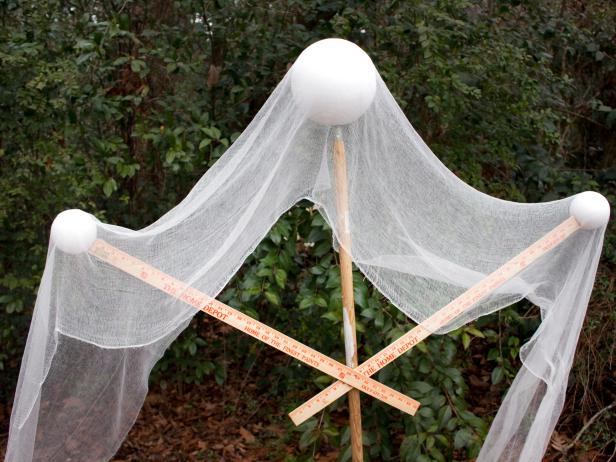 A DIY Halloween ghost is draped with gauze for a spooky front yard decoration.