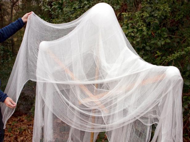 Gauze is draped on the frame of a DIY Halloween ghost for a spooky front yard decoration.