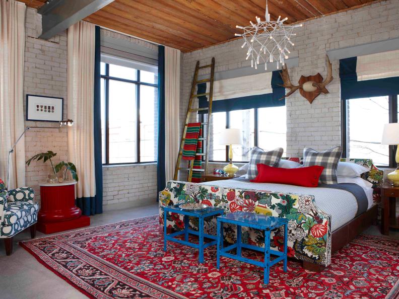 White Brick Bedroom With Red Rug, White Chandelier and Blue Tables