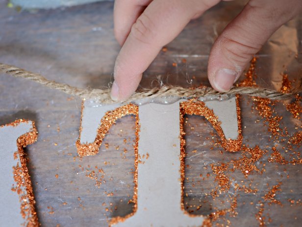 Once dry, use hot glue gun to affix letters to hemp twine. Space the letters approximately one half-inch apart. Leave a four-inch space between words. Loop twine on each end to hang.