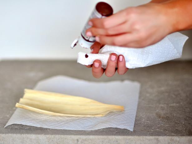 Apply a small dot of wood stain to paper towel and rub onto one side of the corn husks to create a rich color