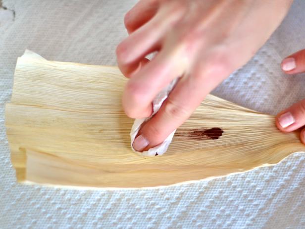 Apply a small dot of wood stain to paper towel and rub onto one side of the corn husks to create a rich color. Tip: Try using colorful stains to achieve a varied effect.