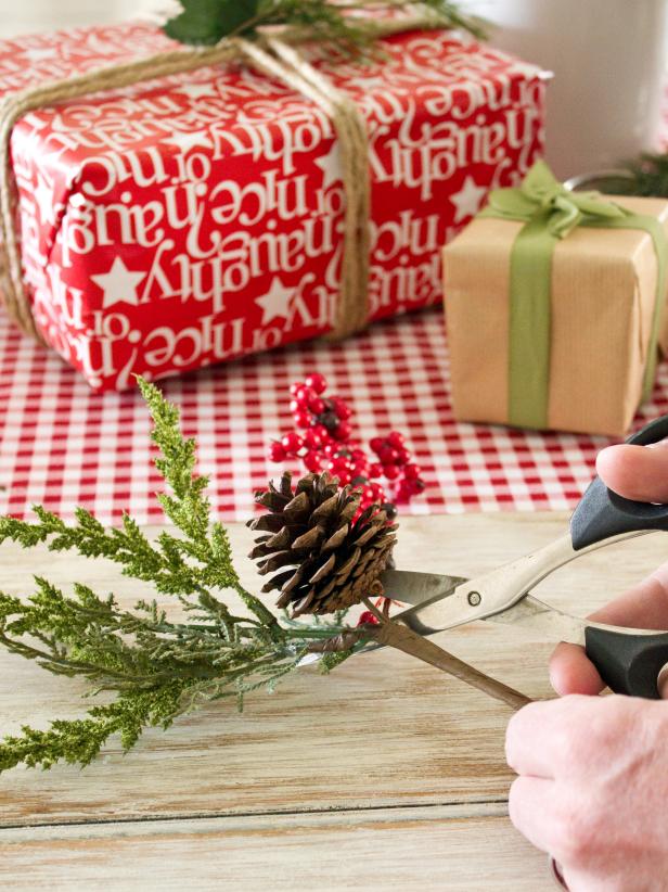 Use scissors to cut apart holiday floral picks, like faux greenery. Tip: Aim for an even mix of flat pieces (like greenery) and larger, 3-D pieces (such as pine cones or holly berries). Leave plastic stems attached; it will be easier to affix each piece to the ribbon.