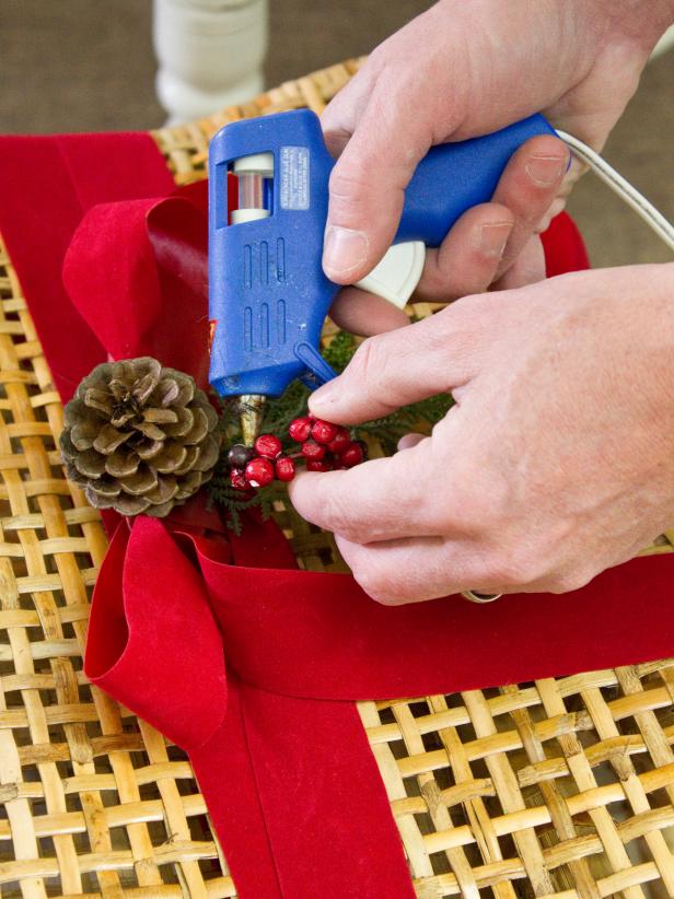Hot Gluing Berries to Red Ribbon on Wicker Dining Chair