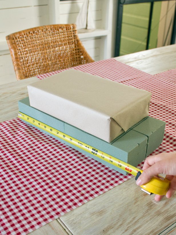 To create a stacked gift box centerpiece, measure each of the four vertical sides and the top portion outside the lines of your floral foam, which will be the base of your stacked gift boxes.