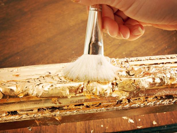 Gently rub mophead brush over gold leaf to buff surface.