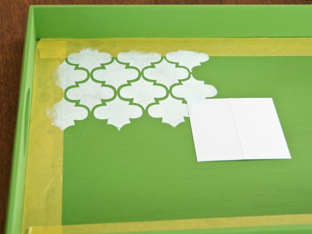 While the freshly stenciled design dries, clean any errant paint off the front side of the stencil to prevent smears. Working in sections, line up the pattern, then repeat the stencil until entire tray is covered with the design. If stencil pattern smears, go over design with an artist's brush to sharpen them up.
