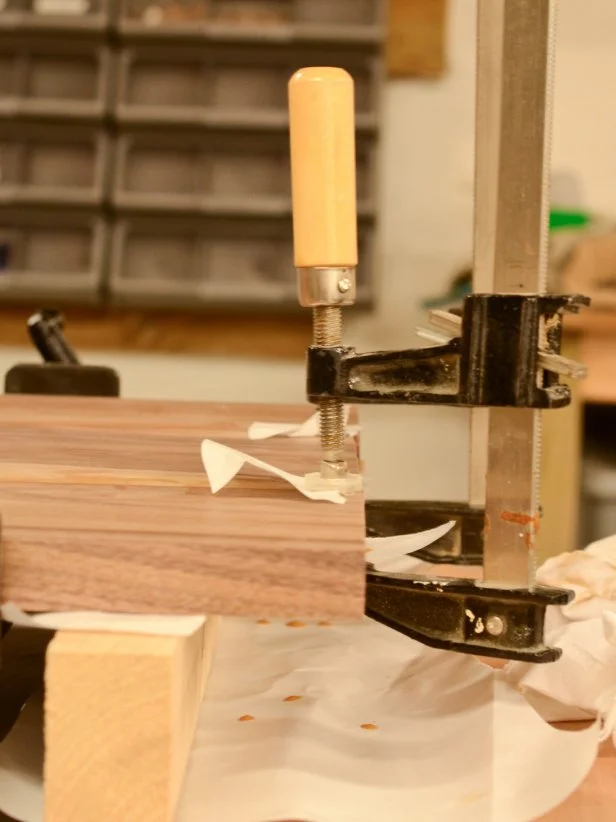 Use small pieces of parchment paper when using clamps on a seam to prevent clamps from sticking to glue. Using a damp rag, wipe away any glue that squeezes out. Allow the board to remain clamped for several hours or overnight.