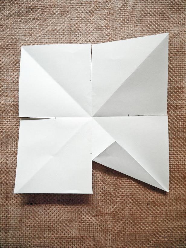 Fold each cut flap toward the diagonal fold lines. Repeat for all four sides until you get a 4-pointed star shape.