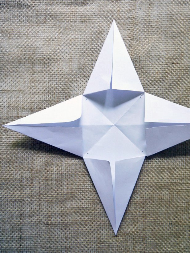 Fold each cut flap toward the diagonal fold lines. Repeat for all four sides until you get a 4-pointed star shape.