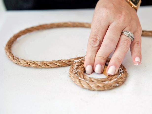To create the base of your basket, apply glue along the first 5 inches of the rope. Coil the rope on a flat surface, applying more glue on every inch of the rope. Keep coiling and adding more rope until you have the circumference of basket you prefer.