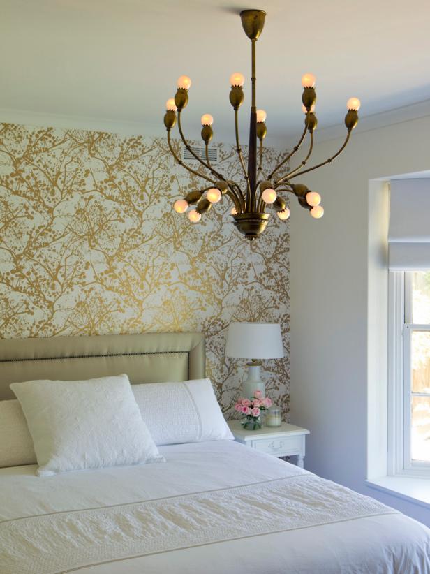 White Bedroom With Gold Wallpaper and Brass Chandelier