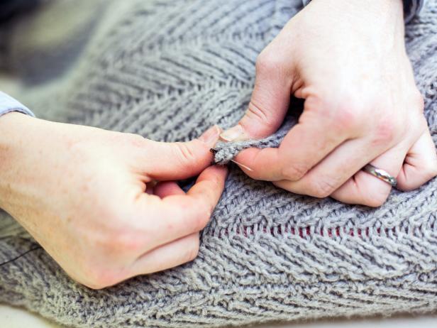 Attaching the sweater's neck to a pillow insert with a stitch. 