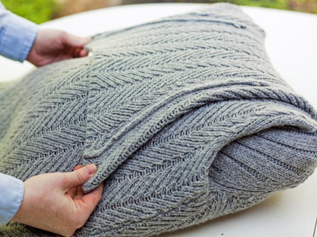 Folding the neck of a sweater on a pillow form. 