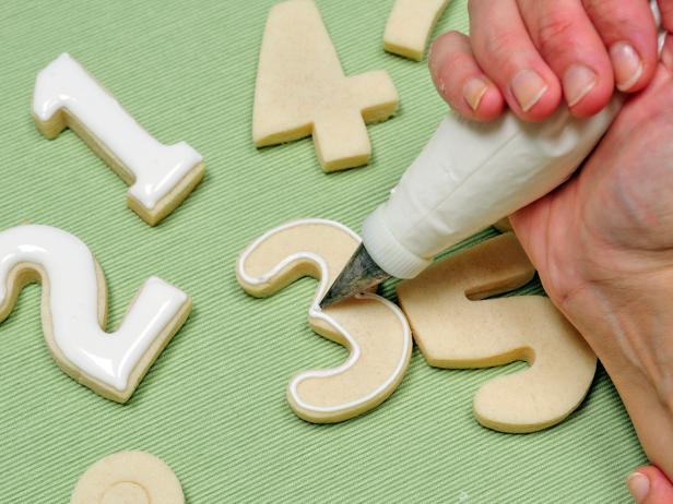 Start by piping thick royal icing all the way around the numbers.