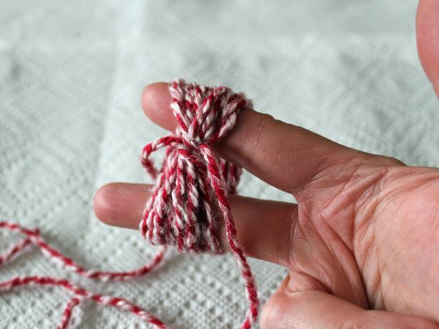 Once the yarn is wrapped around your fingers about a dozen times, tie them together with a separate piece of yarn. To be sure knot it a few times.