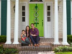 Family sits on front porch with green door