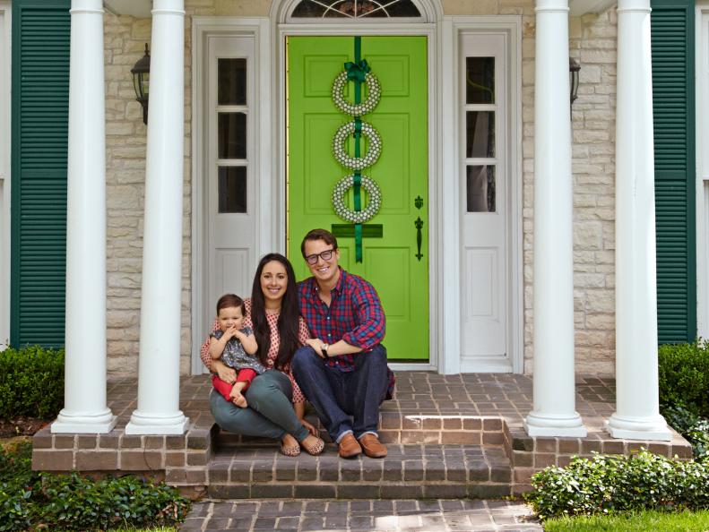 Family sits on front porch with green door