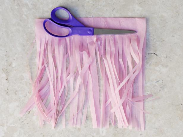 To create tissue paper tassels, cut strips towards the fold to create fringe, leaving about 1 inch uncut at the fold line.