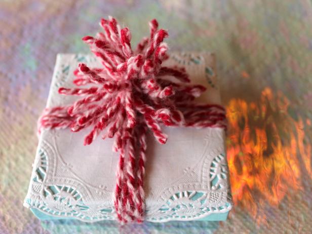 This sweet gift wrap comes together in a snap: Just place the gift in a pretty box and top it with a paper doily held in place with double-sided tape or glue dots. To make the pom-pom, wrap several loops of yarn around your fingers, knot the loops in the middle, then trim the knotted yarn into a rounded pom-pom shape.