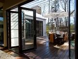 Folding Glass Patio Doors Open to Wood Deck With Dining Area