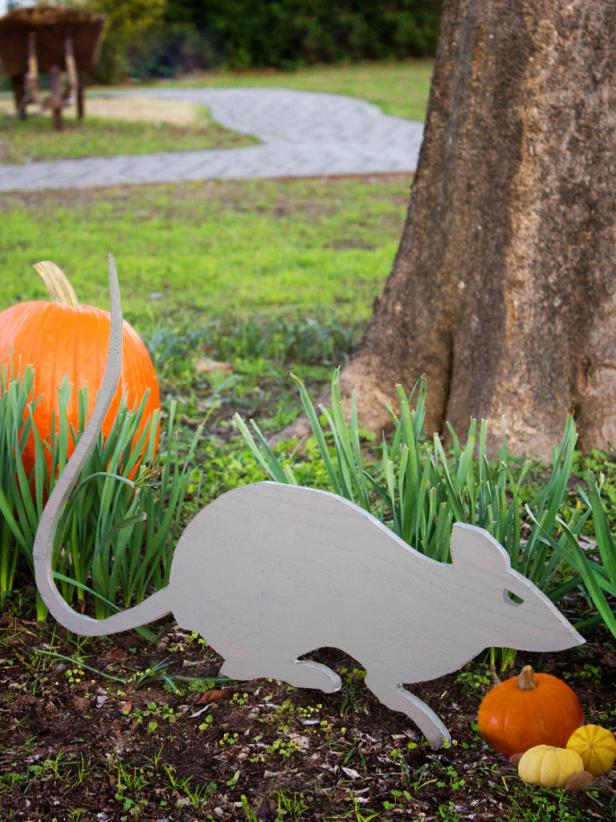 Wooden rat and pumpkins in front yard